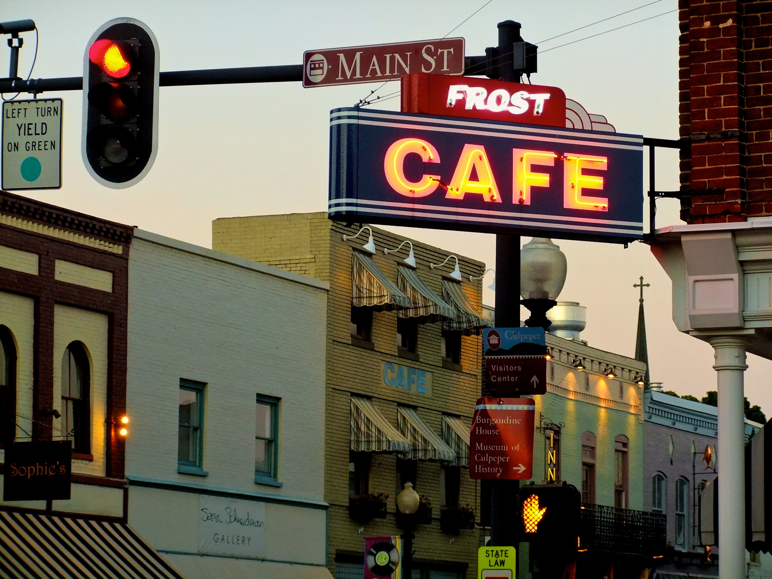 Neon Frost Cafe sign and historic storefronts on Main Street in downtown Culpeper at dusk